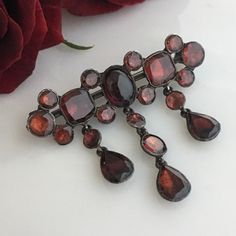 Details: Lovely Georgian Garnet Sterling Silver brooch. Twenty garnets of good size! Large oval cabochon center garnet measures 9mm x 7mm, two larger square garnets are 7mm squared. The garnets have a beautiful deep red to red pink undertone color to them. You will not be disappointed with this piece! Size: Brooch measures 1 3/4 inches wide and hangs 1 1/2 down. Condition: The overall condition of this brooch/pin is very good. Please ask all necessary questions prior to placing an order! Elegant Multi-stone Oval Brooch, Elegant Multi-stone Oval Brooches, Elegant Oval Multi-stone Brooches, Antique Multi-stone Brooches For Formal Occasions, Elegant Multi-stone Brooches For Formal Occasions, Elegant Oval Gemstone Brooches, Formal Fine Jewelry Brooches With Jewels, Elegant Multi-stone Brooches For Gifts, Formal Ruby Brooch Jewelry