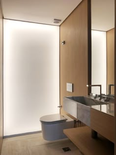 a bathroom with a toilet, sink and mirror in it's center wall is illuminated by recessed lighting