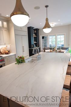 a large kitchen with an island in the middle and two pendant lights hanging from the ceiling