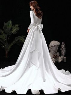 a woman in a white wedding dress standing next to a statue