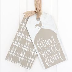 two tags hang on a door with the words farm sweet farm written in white ink