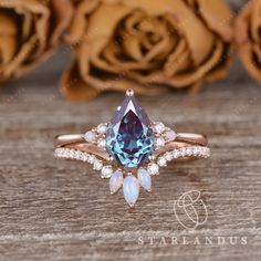 an engagement ring with a blue topazte surrounded by white and pink opals