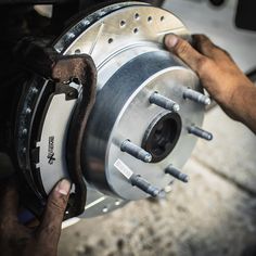 someone is changing the brakes on a car's front wheel and holding it with their hands