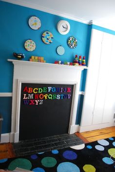 a child's room with blue walls and polka dots on the carpet, white fireplace surround by a blackboard