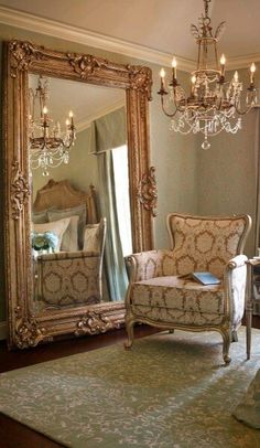 a fancy chair in front of a large mirror with chandelier hanging from the ceiling