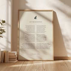 there is a framed book on the floor next to some books and a potted plant