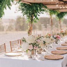 a long table with white and pink flowers is set up for an outdoor wedding reception