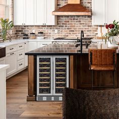 a kitchen with white cabinets and an island in the middle that has wine bottles on it