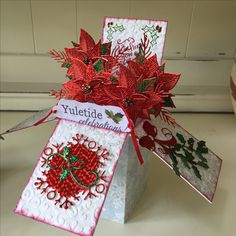 two christmas cards with holly and poinsettis on them sitting in a box