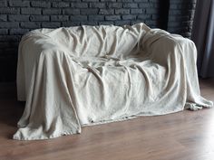 an unmade bed sitting on top of a wooden floor next to a brick wall