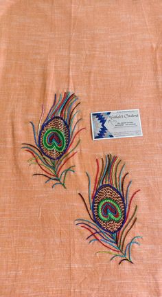 two embroidered peacocks on an orange background