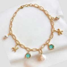 Capture the carefree and relaxed feeling of a day at the beach with our freshwater pearl charm necklace. Gold-filled charms of starfish, baby blue sea glass and merry-go-round pendants on a golden rope style chain add a laid-back luxury of coastal living. The large freshwater pearl adds a hint of sophistication making this necklace a perfect companion for breezy days and beachy nights. Size: 16 inches with a 1 inch extender Blue Charm Necklaces For The Beach, Ocean-inspired Starfish Charm Necklace For Vacation, Vacation Ocean-inspired Starfish Charm Necklace, Beach Starfish Charms Necklaces, Beach Starfish Charms Necklace, Beach Charms Starfish Necklace, Bohemian Pearl Charm Necklaces For Beach, Ocean-inspired Necklaces With Charms For Beach, Ocean-inspired Pearl Charm Necklace For Vacation