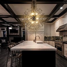 a large kitchen with an island in the middle and lights hanging from the ceiling above it