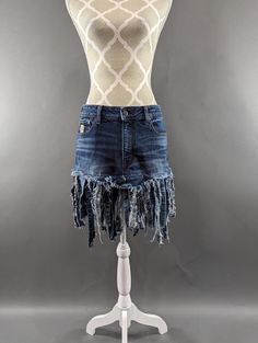 "Upcycled denim skirt with frayed fringe hem. Waist measures 31\", hips 38\" and length is approximately 18\". Super fun!" Summer Dark Wash Skirt With Frayed Hem, Summer Bottoms With Dark Wash And Unfinished Hem, Mid-rise Cotton Denim Skirt With Frayed Hem, High Rise Cotton Denim Skirt With Frayed Hem, Fitted Denim Blue Jean Shorts With Frayed Hem, Short Cotton Skirt With Frayed Hem, Cotton Skirt With Frayed Hem, Short Length, Spring Cotton Jeans With Fringe, Fitted Cutoff Skirt With Frayed Hem