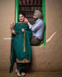 a man and woman standing next to each other near a window with green shutters