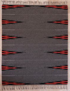 a gray rug with red and black designs on it