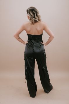 Dress to impress in our Corset Jumpsuit in classic Black. This sleek and stylish one-piece effortlessly combines the edginess of a corset with the ease of a jumpsuit. The black color adds a touch of sophistication, making it a versatile choice for a night out or any special occasion. With its figure-flattering silhouette and fashion-forward design, our Corset Jumpsuit is a must-have in your wardrobe. Zipper closure in the back strap-less Corset top Mesh material on the upper half of the jumpsuit Fitted Sleeveless Satin Jumpsuits And Rompers, Fitted Satin Strapless Jumpsuit For Night Out, Backless Night Out Corset With Boned Bodice, Solid Satin Jumpsuits And Rompers For Night Out, Chic High Waist Corset With Corset Back, Chic Party Corset With Lined Body, Chic Evening Corset With Lined Body, Fitted Satin Jumpsuits And Rompers For Date Night, Chic Backless Corset With Built-in Bra