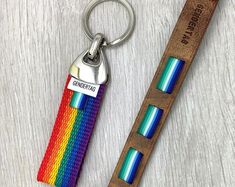 a wooden keychain with a rainbow stripe design on it and a leather strap