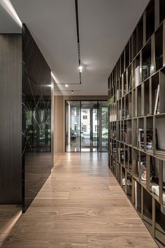 an empty room with bookshelves and wooden flooring in front of glass doors