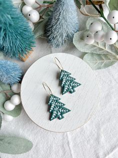 two wooden christmas trees sitting on top of a table next to blue and white decorations