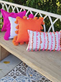 colorful pillows are sitting on a wooden bench