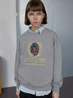 The Classic Sweatshirt depicted here offers a blend of traditional collegiate style and modern casual wear. It features a distinctive crest graphic on the front, with elaborate details and text that reads BRENDA BRENDEN EST. 1980, adding a touch of preppy flair. The gray hue of the sweatshirt makes it a versatile piece that can be easily paired with various outfits, while its crew neck and ribbed cuffs ensure a comfortable and snug fit. - The crest graphic is richly designed, making the sweatshirt stand out as a statement piece while still retaining a classic look.- Made from soft, durable fabric, this sweatshirt provides warmth and comfort, ideal for cooler days.- Its traditional fit and simple color allow it to be styled effortlessly with both casual jeans and more formal trousers.- Collegiate Sweatshirt Outfit, Sweat Shirt Outfits Women, Classic College Sweatshirt With Letter Print, Vintage Sweatshirt With Embroidered Logo For College, Vintage Embroidered Logo Sweatshirt For College, Vintage College Sweatshirt With Embroidered Logo, Classic Letter Print Sweatshirt For Streetwear, Classic Letter Print Sweatshirt For College, Graphic Crewneck Outfit