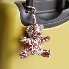 a teddy bear is hanging on the handle of a suitcase