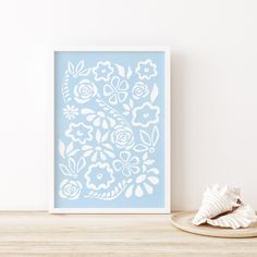 a blue and white floral print sitting on top of a table next to a seashell