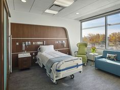 a hospital room with a bed, chair and window overlooking the field outside in front of it