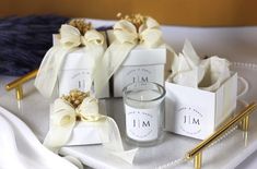 a candle and some small boxes on a white table cloth with gold pins in them