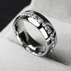 a wedding ring with diamonds on it sitting on top of a white cushioned surface