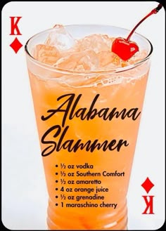 an orange drink with ice and a cherry on the top, surrounded by playing cards