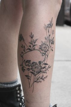 a woman's leg with flowers and a bird tattoo on her left calf area