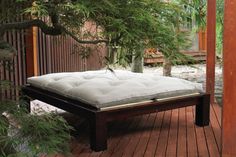 a mattress is sitting on top of a wooden platform in the middle of a garden