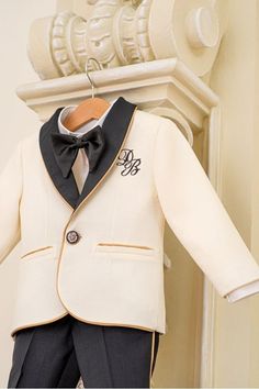 A classic combination of ivory and black with golden details. the jacket is embroidered with the little ones initials. A perfect suit for the Holidays season, a wedding or a baptism! Please measure the little one prior to ordering, to be sure the suit fits him. The measurements that you need to take are. Height Chest Circumference Waist Circumference Hips Circumference Color: black and ivory. Suit components: suit jacket, trousers and shirt with bowtie. Composition: wool, cotton, rayon, viscose Classic Gold Party Sets, Classic Gold Formal Sets, Classic Gold Sets For Formal Occasions, Beige Tuxedo Blazer For Groom, Classic Gold Blazer With Suit Collar, Beige Tuxedo Blazer For Wedding, Gold Tuxedo Suit For Groom, Formal Gold Tuxedo Sets, Classic Gold Long Sleeve Sets