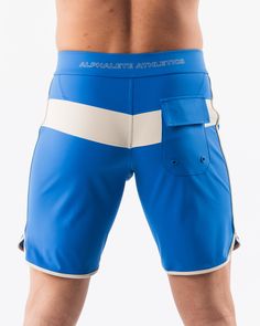 HIGHLIGHTS.. Unlined boardshort. 9” inseam Reflective branding at leg opening and back waistband Elastic waistband with adjustable self-tie drawcords Color-blocking panelling Water resistant fabric FIT SUGGESTION. This item runs true to Alphalete’s standard sizing.. Fit is based off of waist size in inches.. If you are between sizes, we recommend sizing up for a relaxed fit.. Eric is 6’2”/188cm, wearing a size 32. MATERIALS AND WASHING DIRECTIONS. 67% Nylon, 23% spandex. Due to the high saturati Fitted Swim Trunks With Pockets For Sports, Sporty Fitted Surfing Bottoms, Blue Activewear For Summer Surfing, Blue Activewear For Summer Water Sports, Blue Activewear For Water Sports In Summer, Blue Sporty Surfing Shorts, Sporty Blue Surfing Shorts, Blue Sporty Activewear For Water Sports, Sporty Blue Activewear For Water Sports