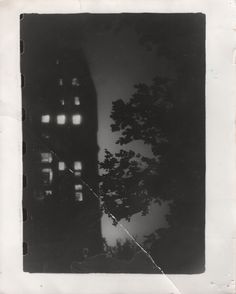 an old black and white photo with trees in front of the building at night time