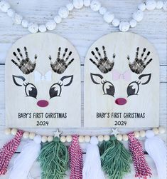 two baby's first christmas handprints on wooden signs with tassels