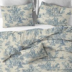 a bed with blue toilers on it and white linens, along with two pillows