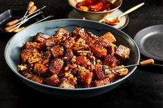 a bowl filled with meat and rice next to chopsticks on a table top