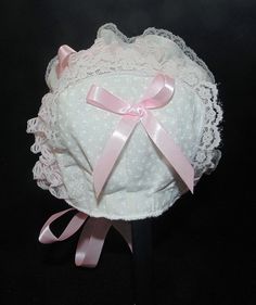 Printed white cotton with pink double sided satin ribbon bows and ties. Bonnet has white lining.. White and pink lace Size / Measurement from under ear lobe around top of head to under other ear lobe preemie/ newborn 10 inches 0-3 months/ 11 inches 3-6 months / 12 inches 6-9 months / 13 inches 9-12 months / 14 inches 12-18 months/ 15 inches 18-24 months / 16 inches Cute White Fitted Bonnet, Cute Fitted White Bonnet, Heirloom Bonnet, Lace Baby Bonnet, Newborn Bonnet, Satin Ribbon Bow, Baby Bonnet, Lace Overlay, Pink Lace