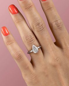 a woman's hand with an orange manicured nail polish and a diamond ring