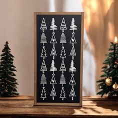 a black and white christmas card on a table with small trees in front of it