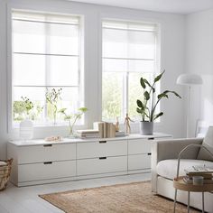 a living room with white furniture and plants in the window sill on the far wall