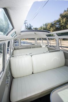 the inside of a white car with two seats on each side and an open window