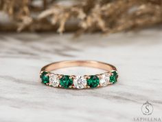 an emerald and diamond band ring sitting on top of a table