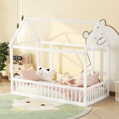 a white dollhouse bed with pink pillows and stuffed animals on the bottom bunk, in a child's room