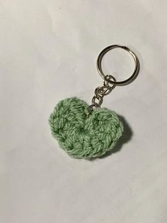 a green crocheted heart shaped keychain on a white surface