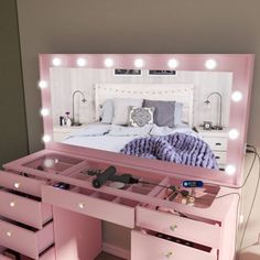 a pink vanity with drawers and lights on it