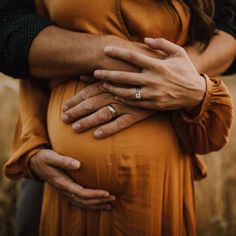 a pregnant woman holding her husband's belly in a field